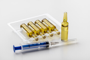 Disposable blue syringe and ampoules with medicine on a white background. Medical and scientific...