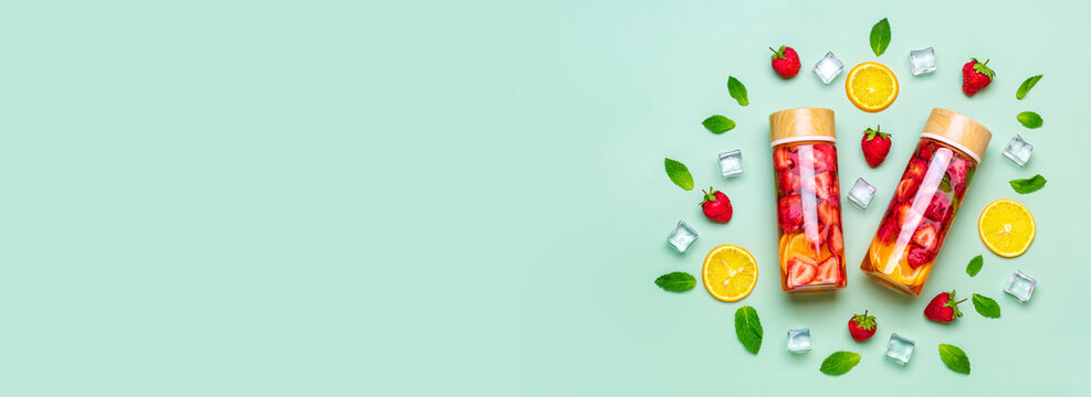 Strawberry infused water, cocktail, lemonade or tea. Summer iced cold drink with strawberry, lemon and lef of mint on green background. Flat lay. Top view.	