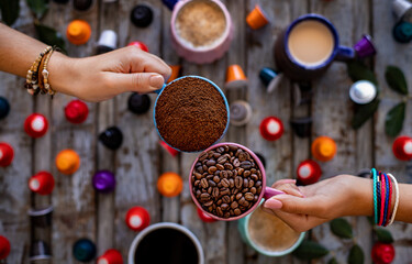 Coffee beans roasted, instant and grinded coffee in the mugs and coffee capsules in the hands of...