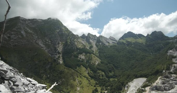 Apuan Alps mountains in Tuscany, green vegetation and blue sky with clouds.The Apuan mountains between the Foce di Giovo and the Passo delle Pecore in Orto di Donna. Apuan Alps, Tuscany, Italy. 