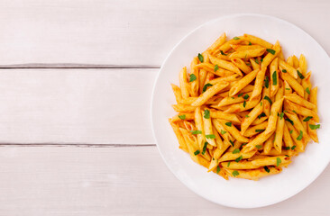 Penne pasta in tomato sauce, decorated with parsley on a white wooden table