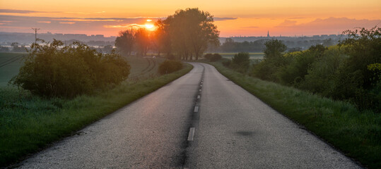 Asphalt road running through the countryside at sunrise