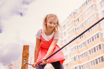 A blonde schoolgirl plays on the playground in the city's backyard