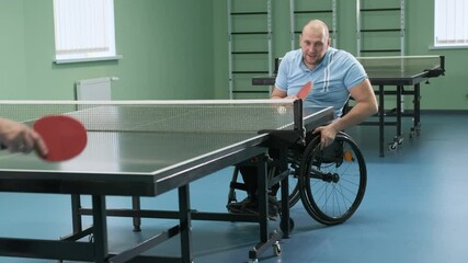 A man in a wheelchair plays ping pong. People with disabilities play table tennis. Rehabilitation of the disabled. Sport.
