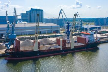 Fototapeta premium An aerial drone view of the industrial port in the Baltic Sea. There is a ships under load in the harbor. 