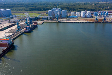 An aerial drone view of the industrial port in the Baltic Sea. There is a ships under load in the harbor.	