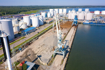 An aerial drone view of the industrial port in the Baltic Sea. There is a ships under load in the harbor.	