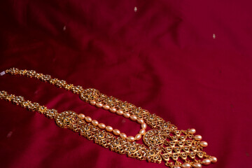 Indian traditional gold Indian wedding women's jewelry on red saree background. Close-up. Still-life.