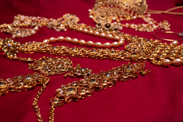 Indian traditional gold Indian wedding women's jewelry on red saree background. Close-up. Still-life.