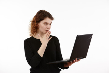 A young slender girl in black clothes works on a laptop. Figure isolated on a white background.