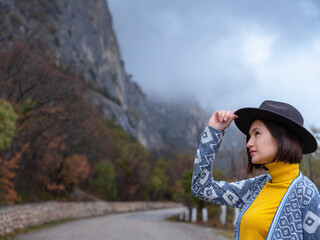 Stylish hipster woman in a hat walking down a mountain road