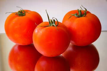 Several red tomatoes on a mirror surface