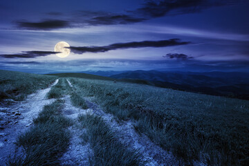 country road through alpine meadow at night. beautiful nature landscape in summer. scenery with...