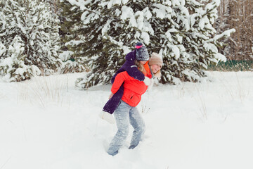 Fototapeta na wymiar mother Carrying daughter Piggyback Having Fun In Winter Forest