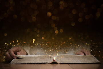 A person reading a Holy Bible with gold background. 