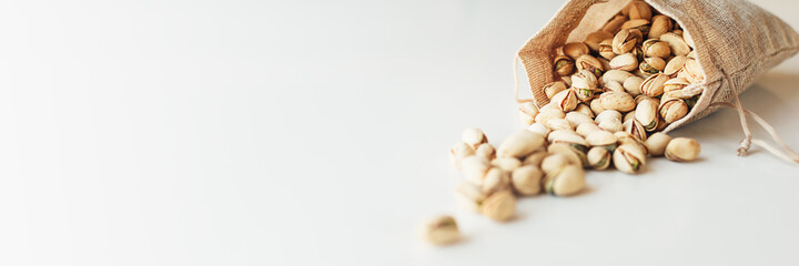 Pile of pistachios on the light background. Pistachio is a healthy vegetarian protein nutritious food. Vegetarian food concept. Banner.