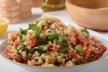 Tabbouleh - a Middle Eastern cuisine vegetarian salad with chopped parsley, tomatoes, mint, onion and bulgur, and seasoned with olive oil, lemon juice.