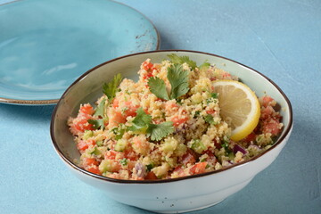 Tabbouleh - a Middle Eastern cuisine vegetarian salad with chopped parsley, tomatoes, mint, onion and bulgur, and seasoned with olive oil, lemon juice.