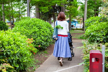 公園をベビーカーを押して歩くお母さん