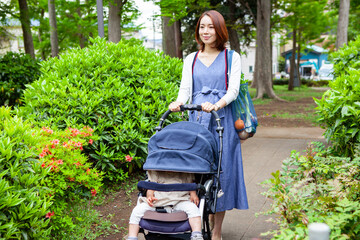 公園をベビーカーを押して歩く、妊娠中のお母さん