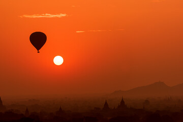 Hot air balloon close to the sun over temples of Bagan, Myanmar at sunrise.