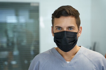 Young male doctor wearing mask and posing for camera