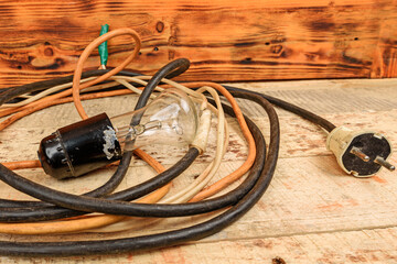 Old portable lighting lamp with wire on wooden background