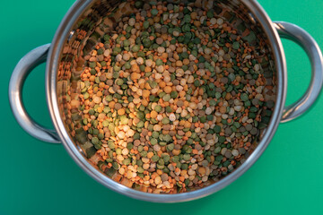 a metal pan with legumes for cooking. against the background of sea green.