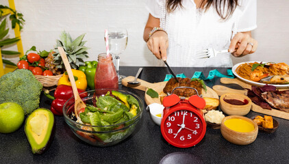 Selective focus of Red clock and organic chipotle pork which young woman  she is Intermittent fasting eating salad  and healthy food  lifestyle concept image