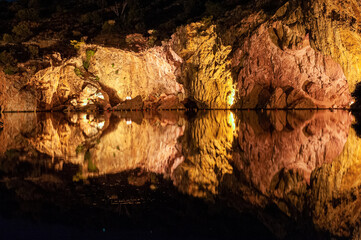 illumineted caves miroring in still waters of vouliagmeni lake in the night