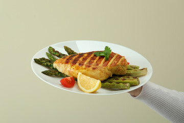 Female hand hold board with grilled chicken and asparagus