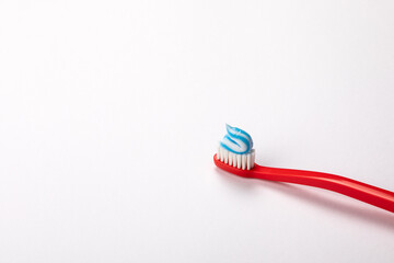 Toothpaste on a red toothbrush. White background with space for text and information