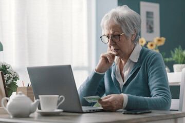 Confused senior woman using her credit card online