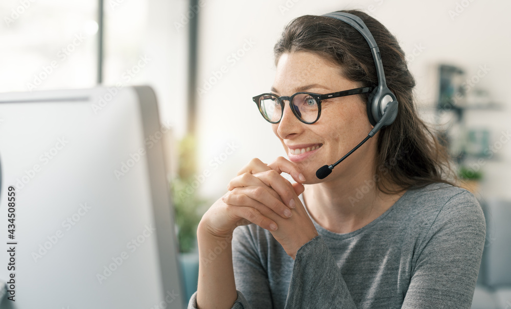 Wall mural woman wearing a headset and working with her computer