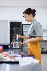 A bright girl cooks sweet dishes at a small production facility