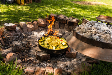 Cooking traditional dalmatian, croatian, bosnian dish called peka. Meat, potatoes and vegetables in...