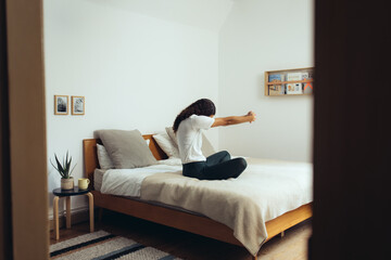 Frau macht Yoga und Dehnübungen zur Entspannung zuhause auf dem Bett