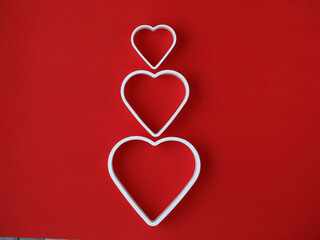 symbol of a family of two adults and one child in the form of three cutters hearts in line on bright red background. horizontal, copy space