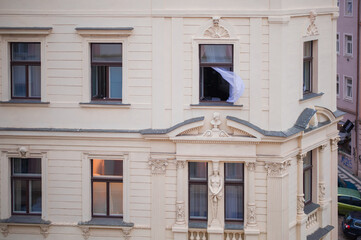light translucent curtain waving from a window on the beautiful facade of the old European city