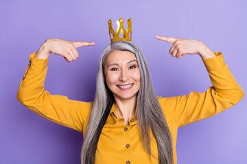 Portrait of nice elderly retired cheerful woman demonstrating crown charisma wealth isolated on...