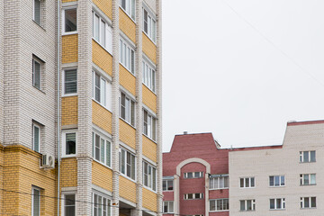 Residential buildings with yellow and red balconies. Against the background of the gray sky. Modern new buildings, building facades. Real estate and urban architecture concept.
