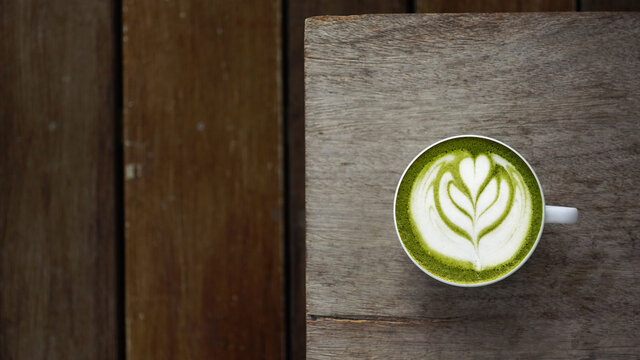 A cup of green tea matcha latte on wooden background                                                                                                                                                    