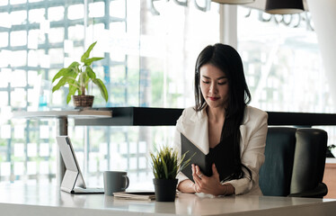 Young businesswoman working in office, checking schedule from book.