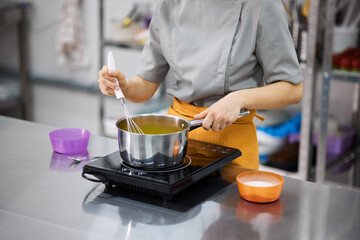 A bright girl cooks sweet dishes at a small production facility