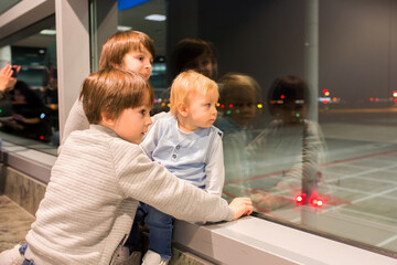 Fototapeta premium Children, traveling together, waiting at the airport to board the aircraft