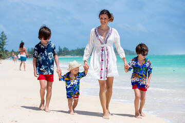 Mother and children playing at tropical beach. Family sea summer vacation. Mom and kids, boys, play in the water. Ocean and water fun for parent and kids. Fit and healthy family