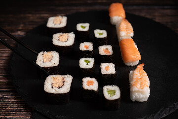 Sushi sind aufgelegt auf der schwarzen Platte Schwarze Stäbe fassen ein Sushi an. Sehr gut...