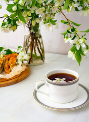 A cup of black tea in white apple blossoms