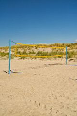 Beach with a playing field for beach volleyball in front of a sky
