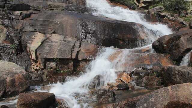 a mountain waterfall with clear water flows among large brown stones. beautiful mountain stream bubbling water